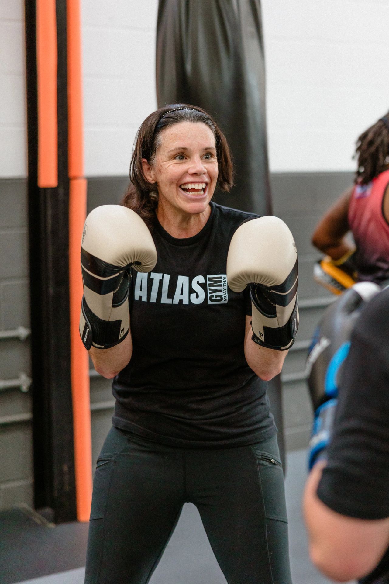 A smiling Atlas Muay Thai student wearing boxing gloves during training